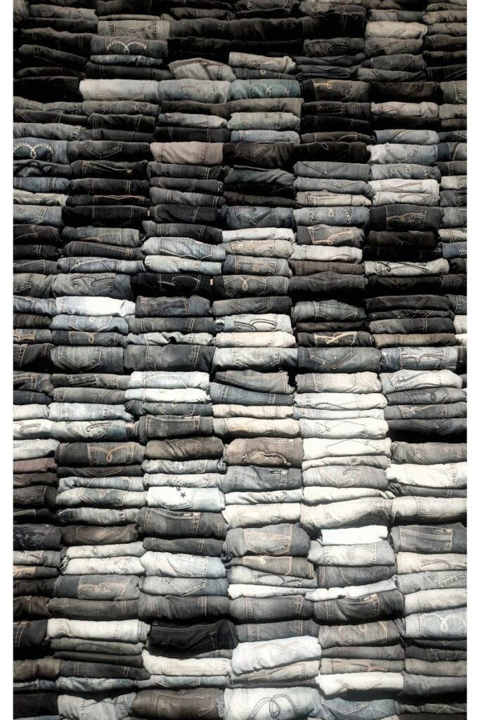 What Not to Bring on a Bikepacking Trip (Real Mistakes) A large vertical stack of folded denim jeans showcasing texture and textile patterns.